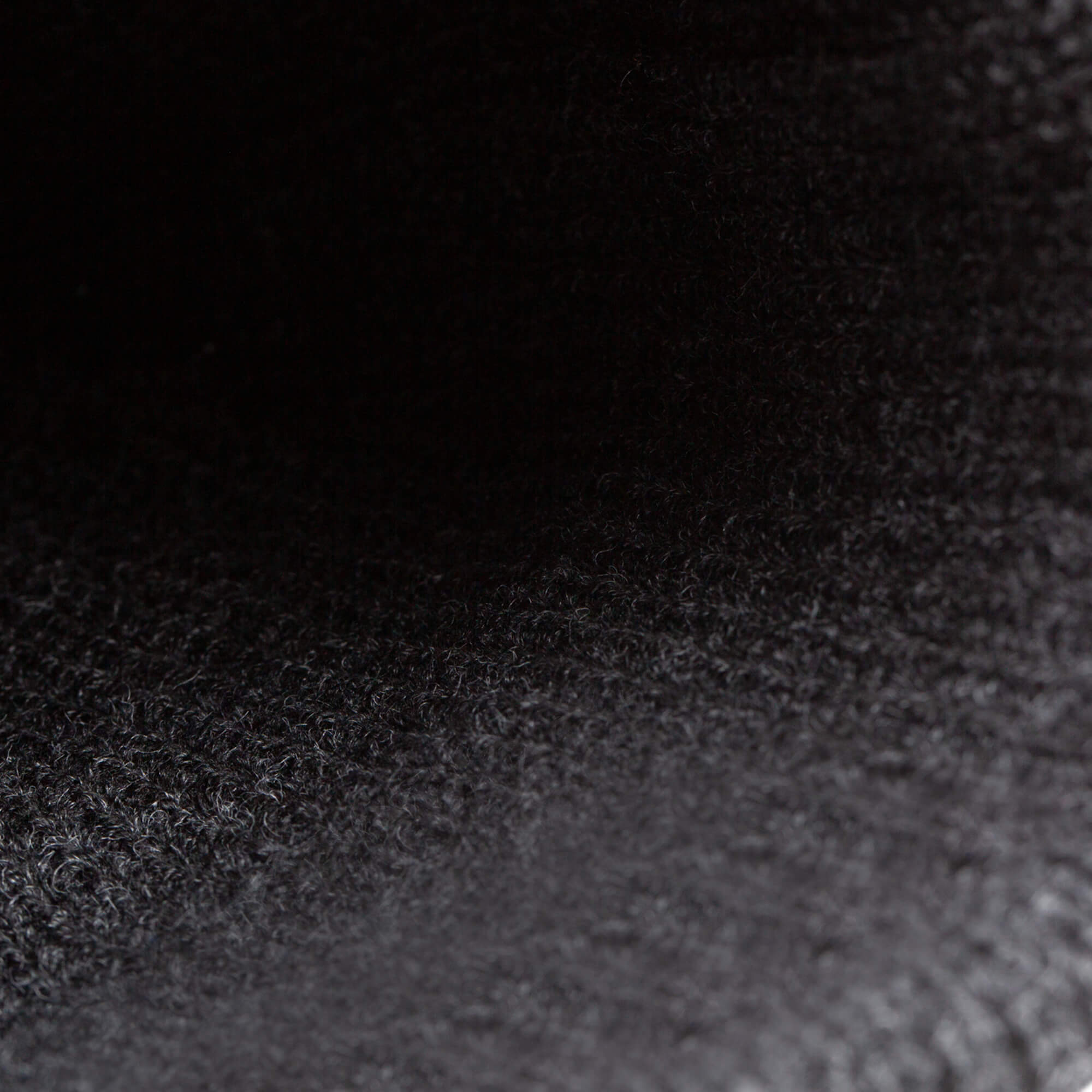 Close-up image of the textured black surface of The Beware Dog Beanie by Goorin Bros., showcasing visible fibers and a gradient of light and shadow—highlighting the heavyweight knit material.