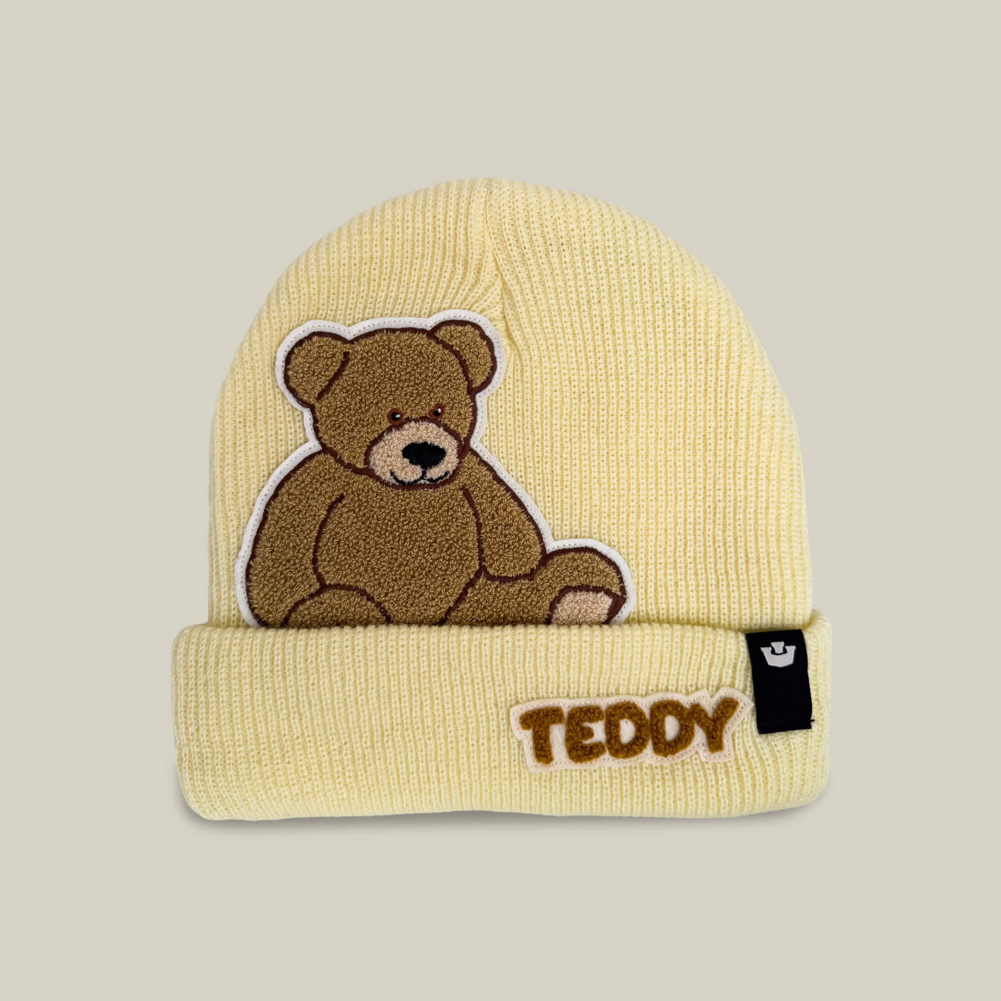 Introducing the Double Stuffed - Teddy Beanie - big by Goorin Bros., a cozy oversized knit beanie in Wax—a light yellow hue. Featuring an embroidered teddy bear and the word “TEDDY” on the folded brim, plus a small black tag on the side, this beanie offers soft warmth that’s perfect for chilly days.