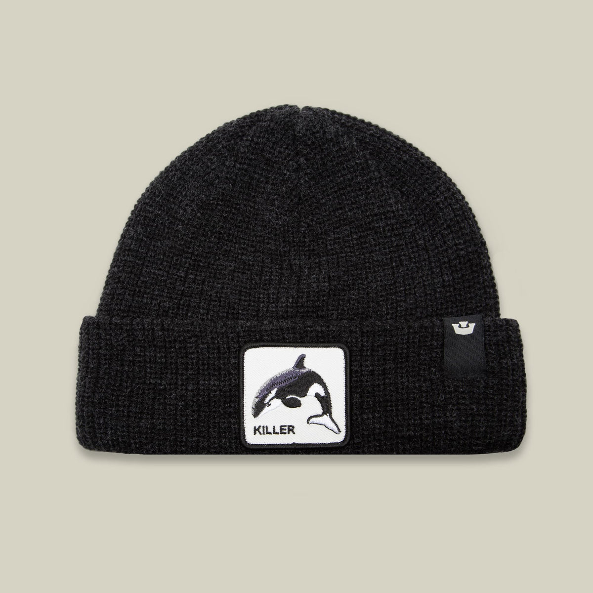 The Killer Whale Beanie by Goorin Bros is a black ribbed knit winter hat featuring a white patch with an orca graphic and "killer" text on the front, shown against a neutral background.