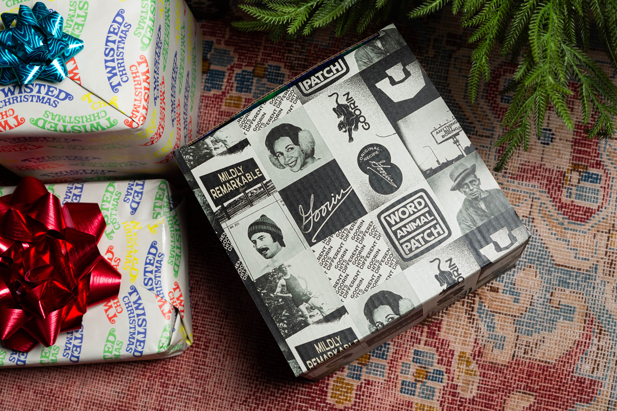 The Goorin Gift Box by Goorin Bros., wrapped in black-and-white collage paper with vintage photos and text, is perfect for headwear fans and sits next to a festive Christmas package topped with a red bow.