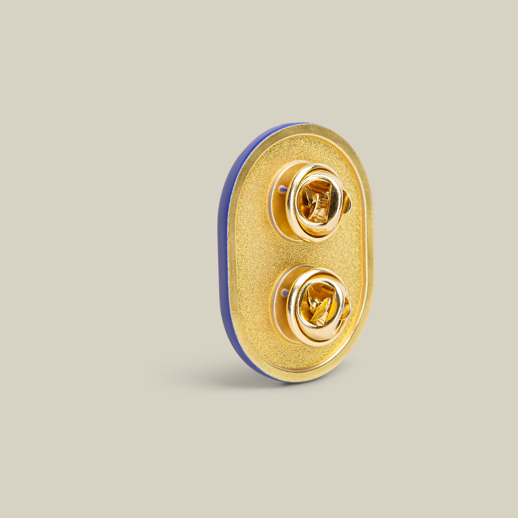 The GO Bananas Pin by Goorin Bros. is an oval accessory featuring a playful blue and yellow design, complete with two gold butterfly clutch fasteners on a neutral background.