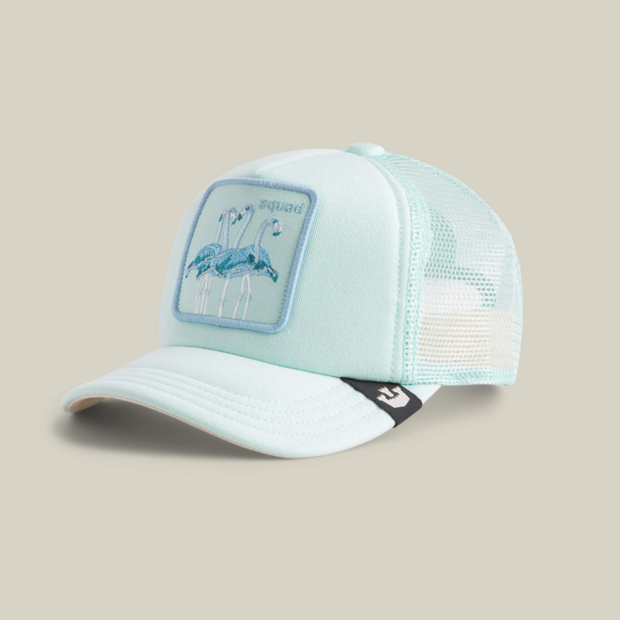 The Lil Squad by Goorin Bros. is a light blue mesh trucker hat with an embroidered patch of two flamingos on the front and a small black and white logo tag on the side of the bill.