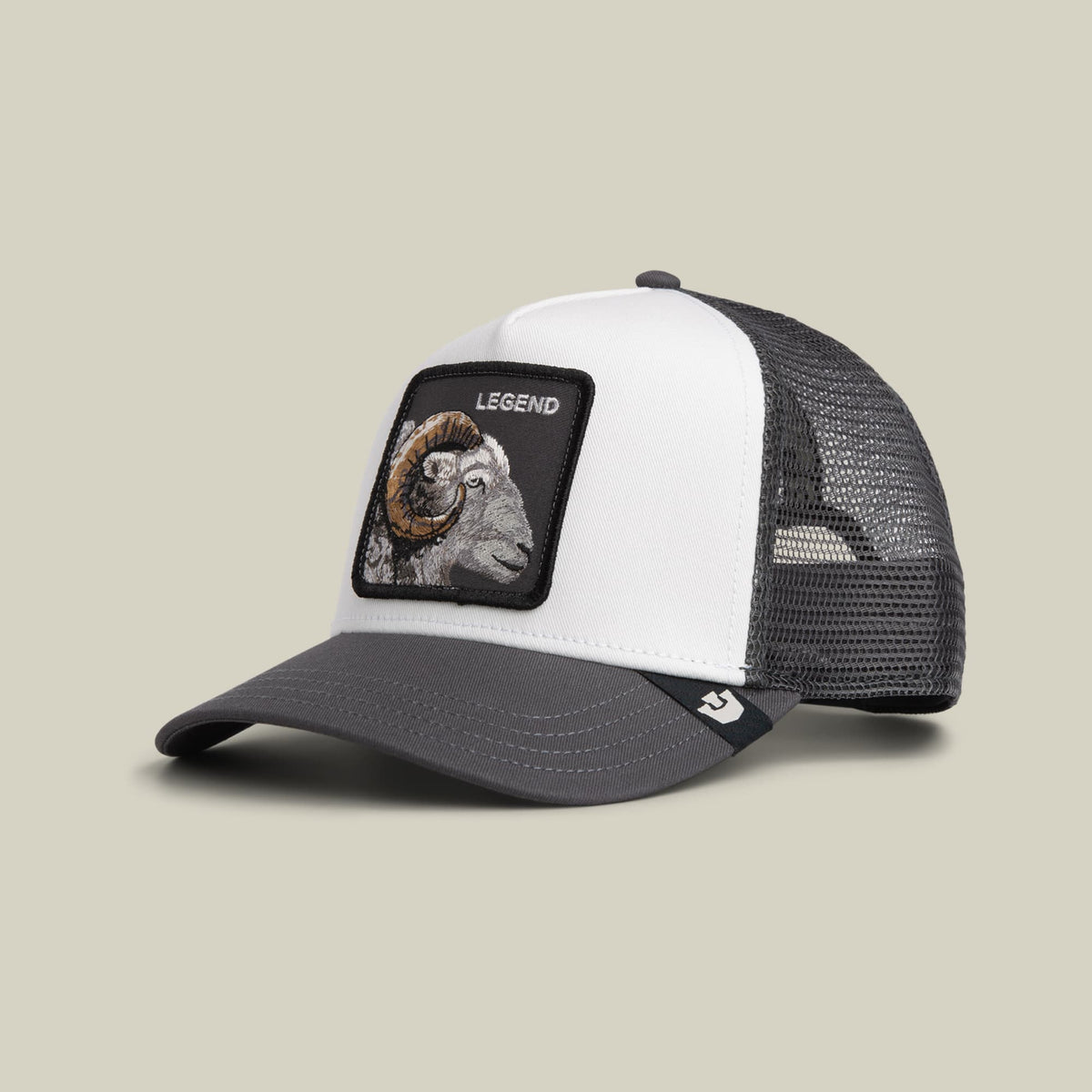 The Goorin Bros. Legend Trucker Mini features a colorblock design with a white front panel, black bill, and charcoal mesh back, accented with an embroidered goat patch labeled "Legend" on the front.
