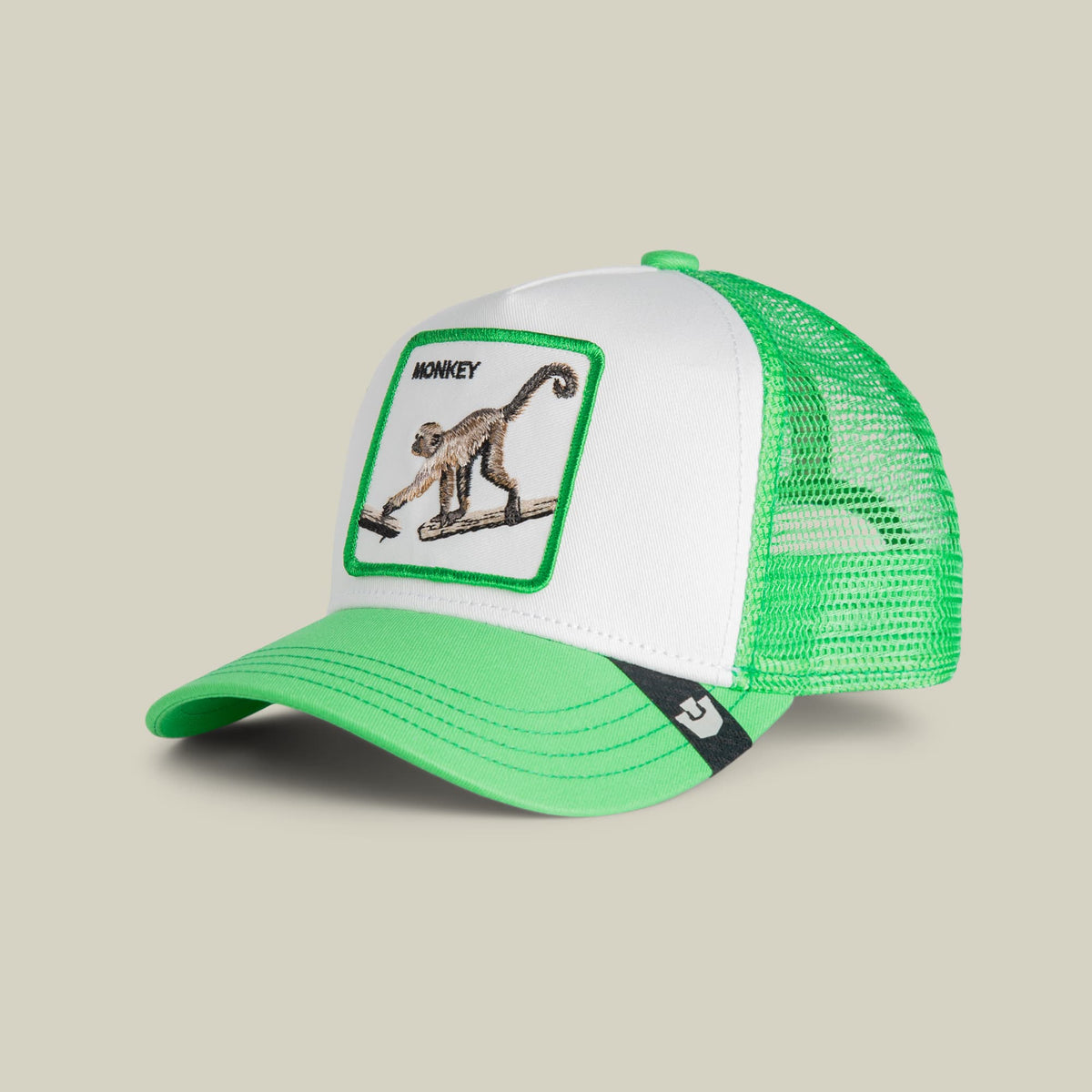 The Goorin Bros. Monkey Mini trucker hat features a white front panel with an embroidered monkey patch, green mesh back, green visor, and black accent stripe. Studio product shot on neutral background.