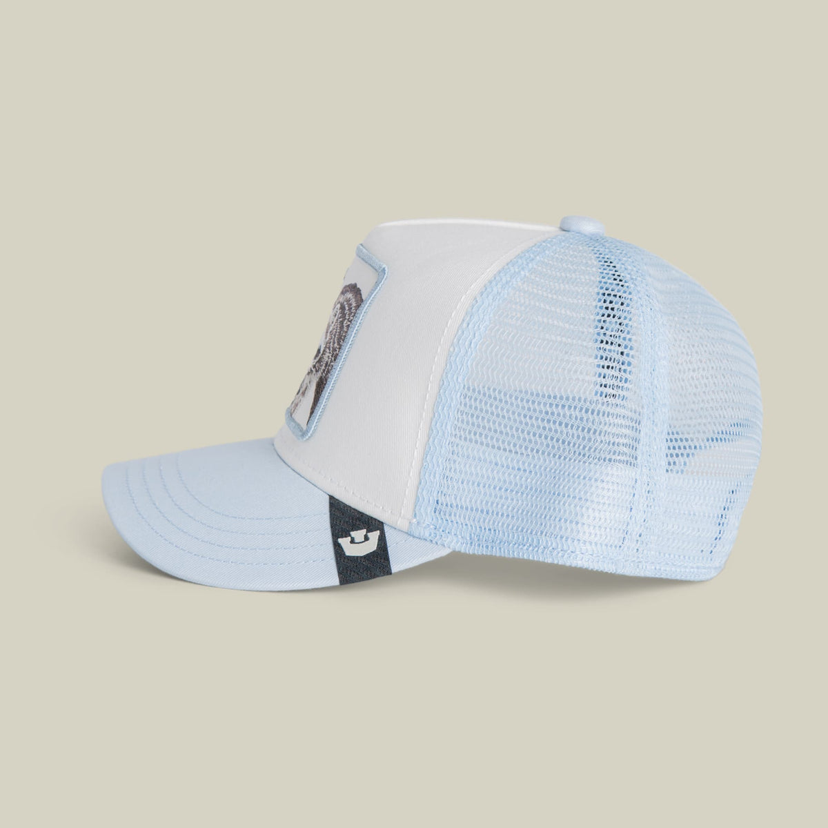 The Goorin Bros. Rascal Raccoon Mini trucker hat features a light blue and white colorway with mesh back paneling, embroidered raccoon patch on the front, and an adjustable black strap, shown against a neutral background.