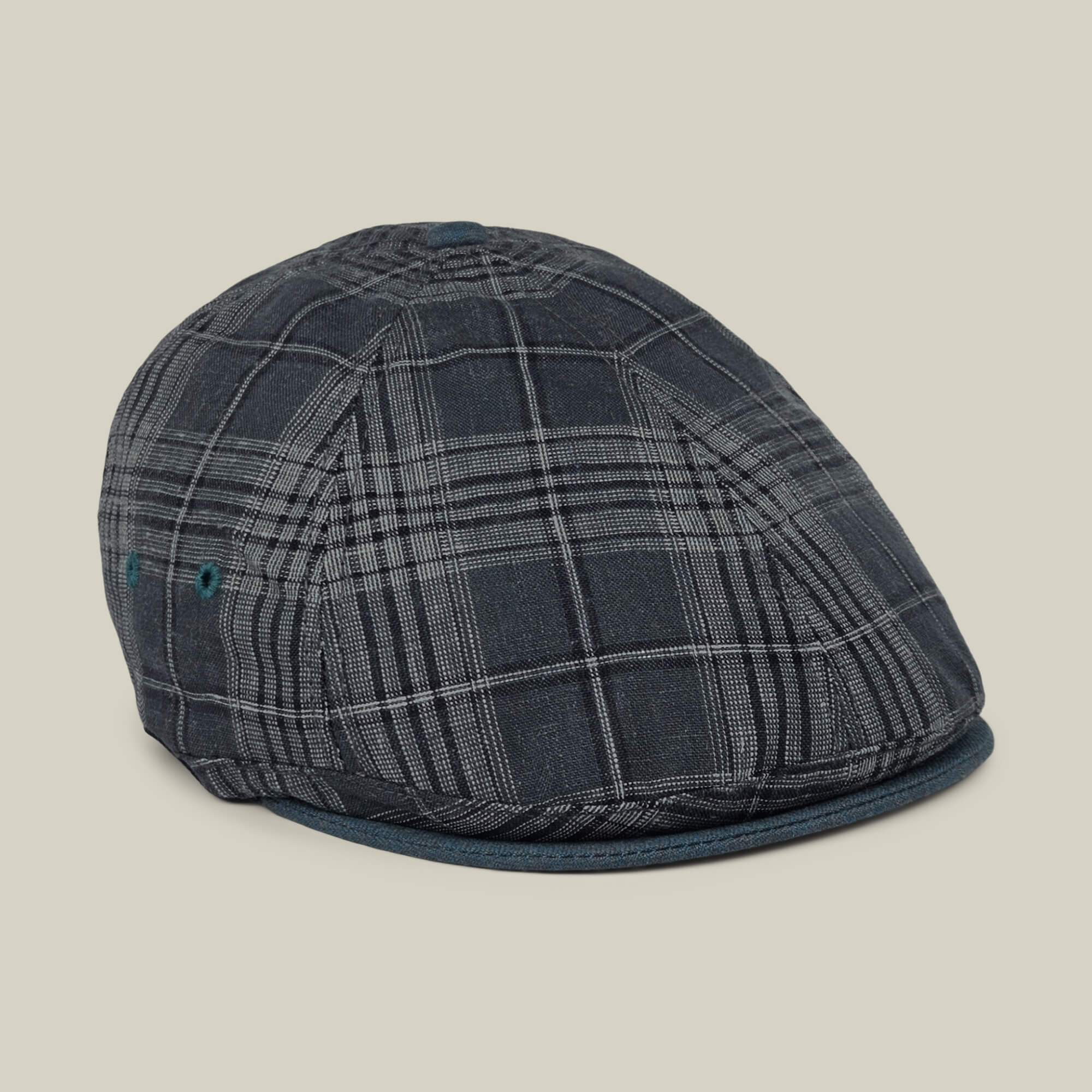 The Goorin Bros. “Point Lobos” is a dark gray plaid 6-panel Ivy flat cap featuring blue accents, handmade in the USA from a breathable cotton blend, and is displayed against a plain light beige background.