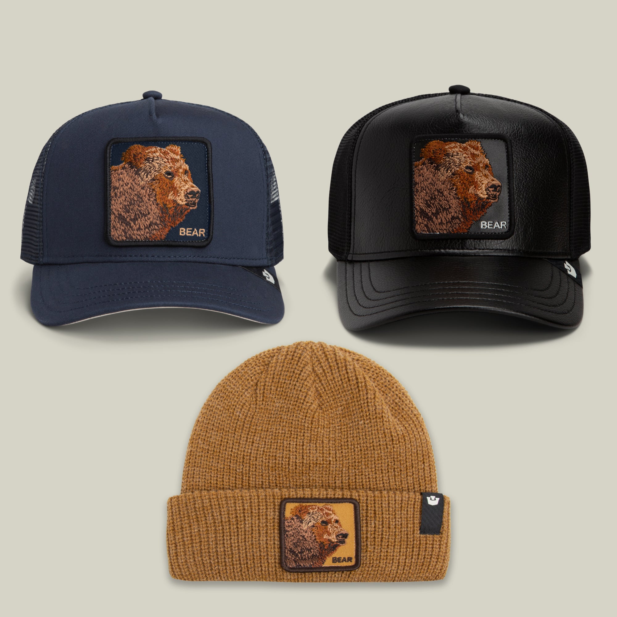 The All Bear, No Bite Bundle by Goorin Bros. includes two trucker hats and one camel beanie, each adorned with a bold bear-head patch on the front and showcased against a neutral background.
