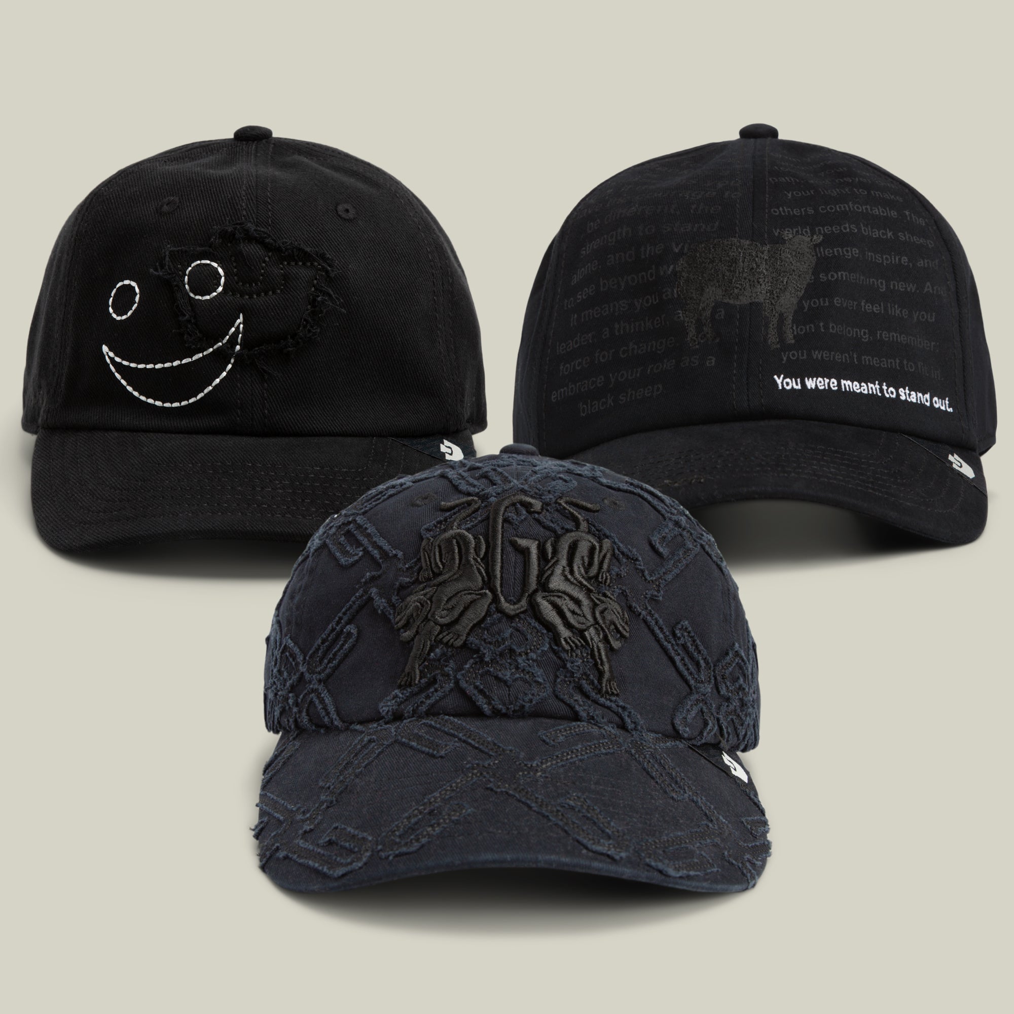 Three black baseball caps from Goorin Bros.’ The Dad Who Stepped Up Bundle are displayed against a light background, featuring unique embroidered designs and text, including a striking longhorn silhouette and a playful smiley face on textured pattern caps.
