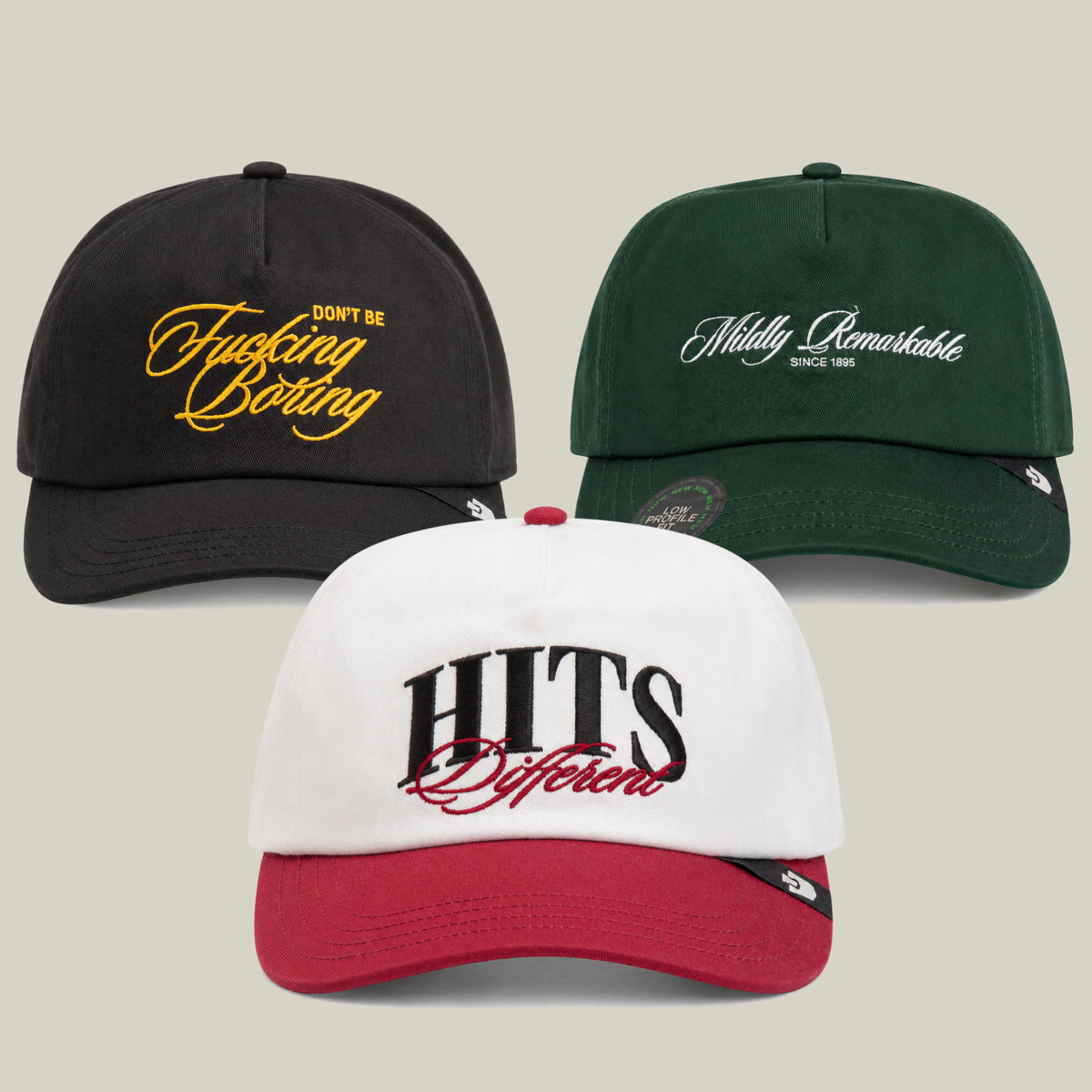 The Don’t Tell Me What To Do Bundle by Goorin Bros. features three baseball caps with embroidered text: a black cap boldly declaring Don’t Be Fucking Boring, a green cap that says Mildly Remarkable Since 1995, and a standout white and red HITS Different cap.