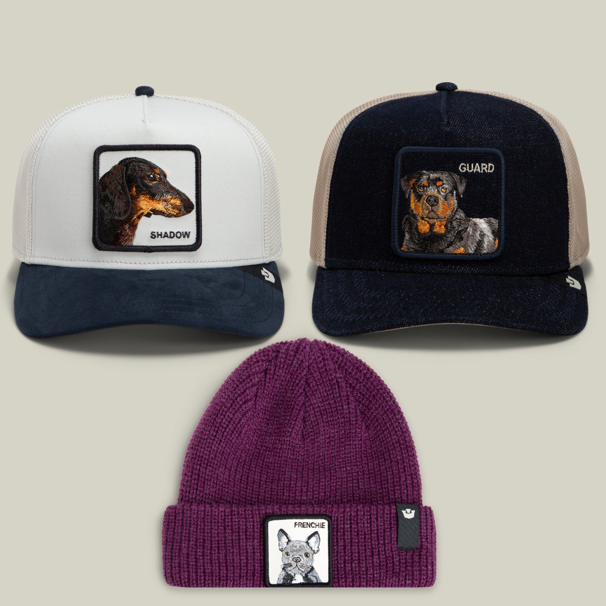 The Good Boys Club Bundle by Goorin Bros. includes three hats: a dachshund trucker hat with an embroidered SHADOW patch, a rottweiler trucker hat with a GUARD patch, and a purple French Bulldog beanie featuring a FRENCHIE patch—all showcased on neutral backgrounds.