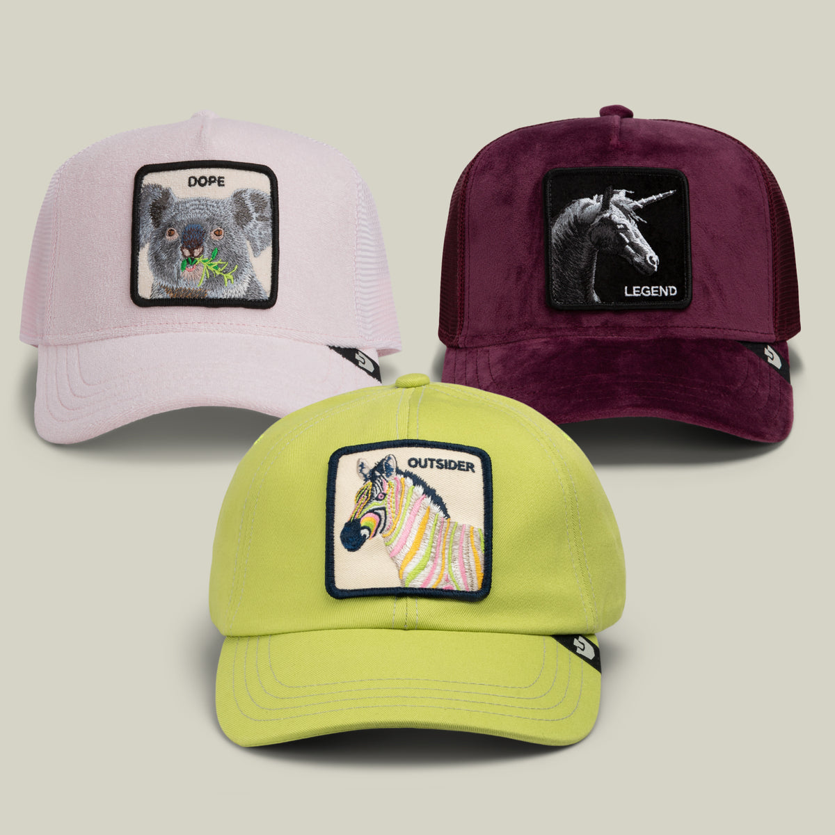 The Goorin Bros. Color Lover Bundle includes three trucker hats with animal patches: a pastel pink hat featuring a koala labeled “DOPE,” a deep wine hat with a unicorn labeled “LEGEND,” and a chartreuse hat with a zebra labeled “OUTSIDER.”.