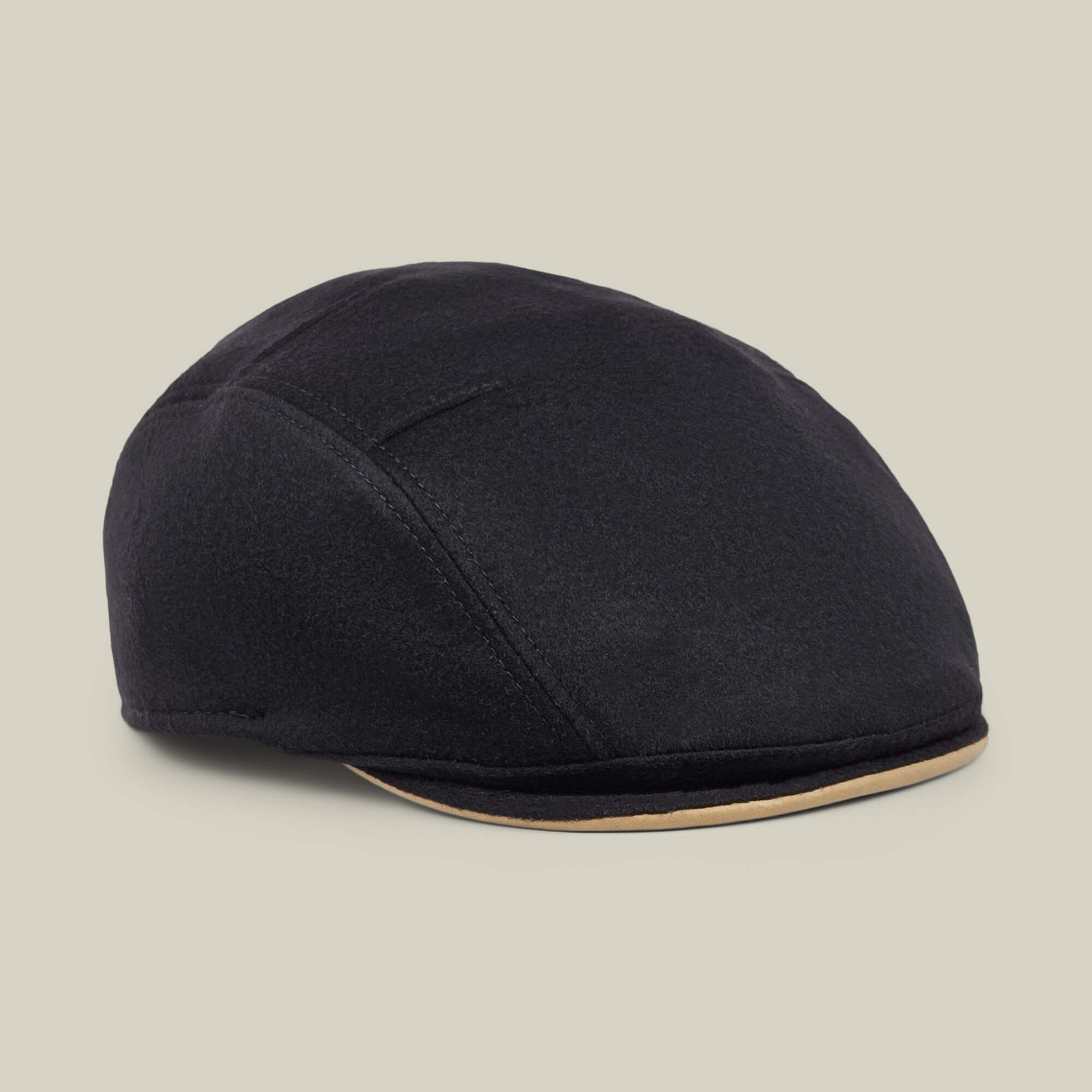 The Goorin Bros. “Cornerstone” is a black wool flat cap, handmade in New Jersey, featuring subtle stitched details and a contrasting beige trim along the brim, displayed on a neutral background.
