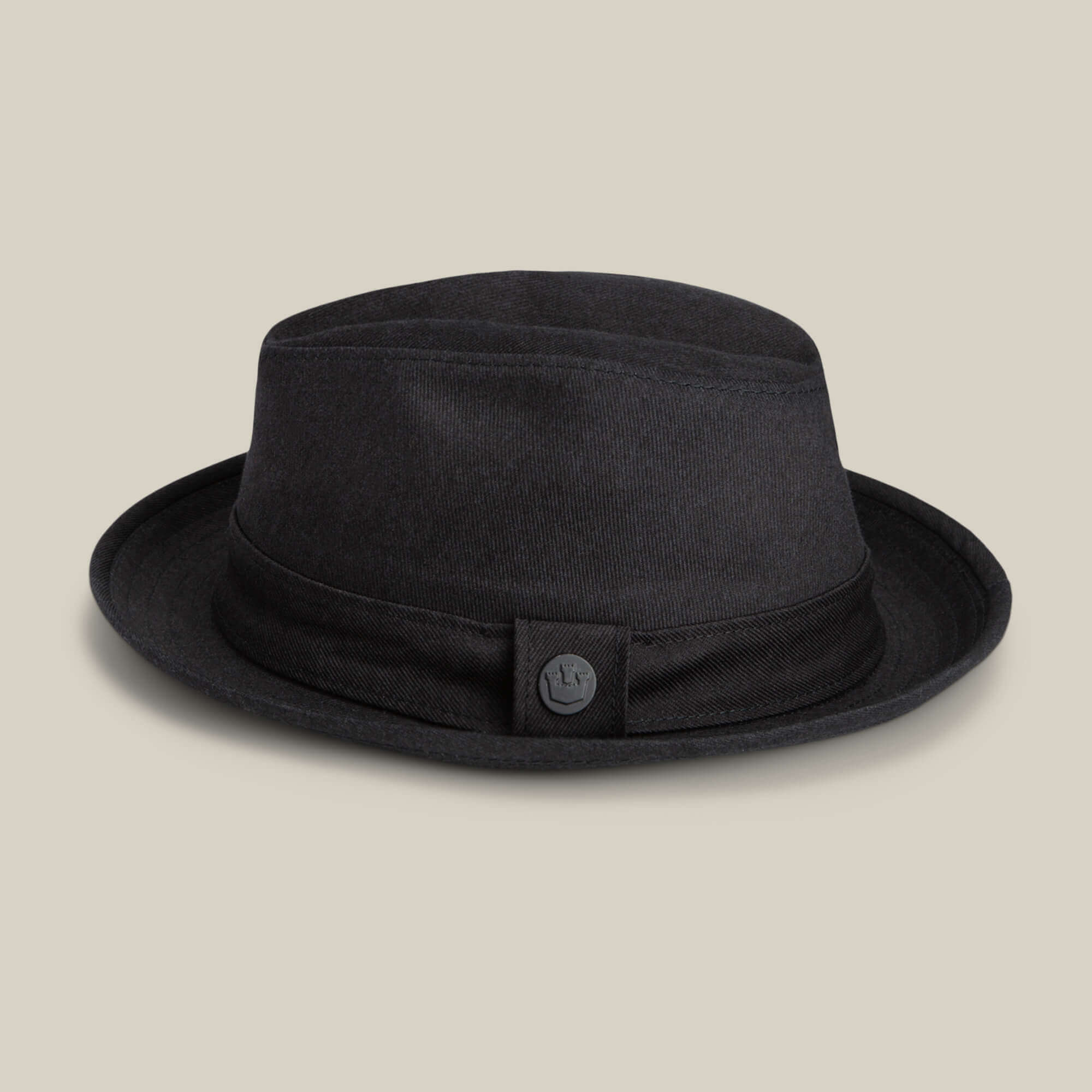 The Goorin Bros. Big Stepper is a stylish black fabric bucket hat with a short brim and button detail on the band, shown against a beige background.