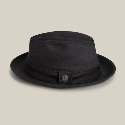 The Goorin Bros. Big Stepper is a stylish black fabric bucket hat with a short brim and button detail on the band, shown against a beige background.