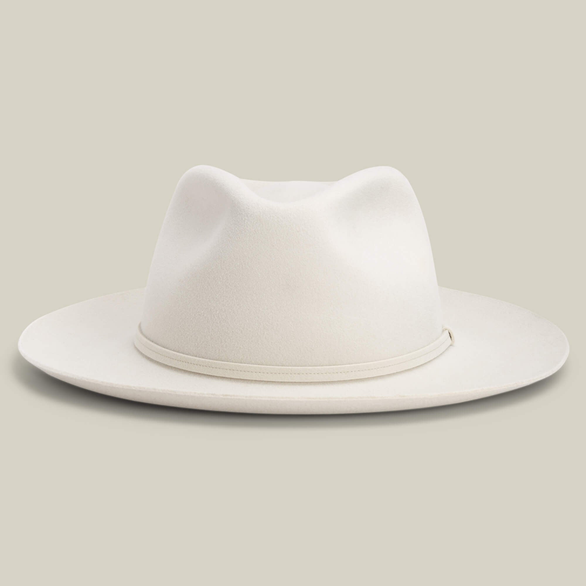 The Night Hawk by Goorin Bros. is a cream-colored fedora with a teardrop crown, wide snap brim, and matching hatband—an elegant all-season hat, shown against a plain light background.