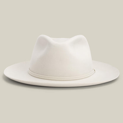 The Night Hawk by Goorin Bros. is a cream-colored fedora with a teardrop crown, wide snap brim, and matching hatband—an elegant all-season hat, shown against a plain light background.