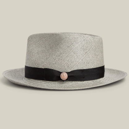 The Goorin Bros. John Sr. is a light gray toquilla straw teardrop fedora with a black ribbon band and round metallic emblem, providing stylish 50 UPF sun protection, shown against a plain background.