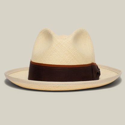 The Hartman by Goorin Bros. is a beige straw fedora with a wide brim, contrast edge binding, and a dark brown grosgrain hat band, shown against a neutral background.
