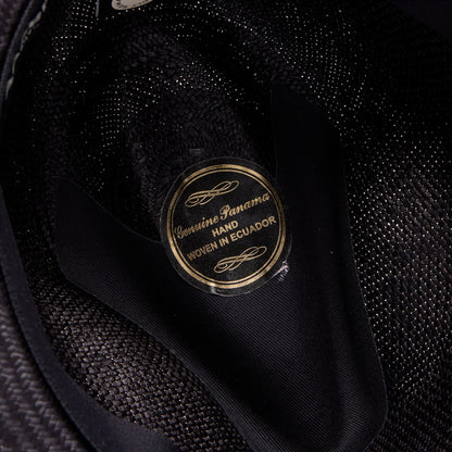 Close-up of a Goorin Bros. Hartman hat’s interior label reading “Genuine Panama, Hand Woven in Ecuador” in gold and black, crafted from 100% toquilla straw and finished with a neat grosgrain hat band.