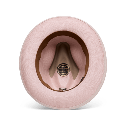 A top-down view of the Hartman by Goorin Bros., a pink hat showcasing its interior with a brown grosgrain hat band, contrast edge binding, and a black and gold label at the center.