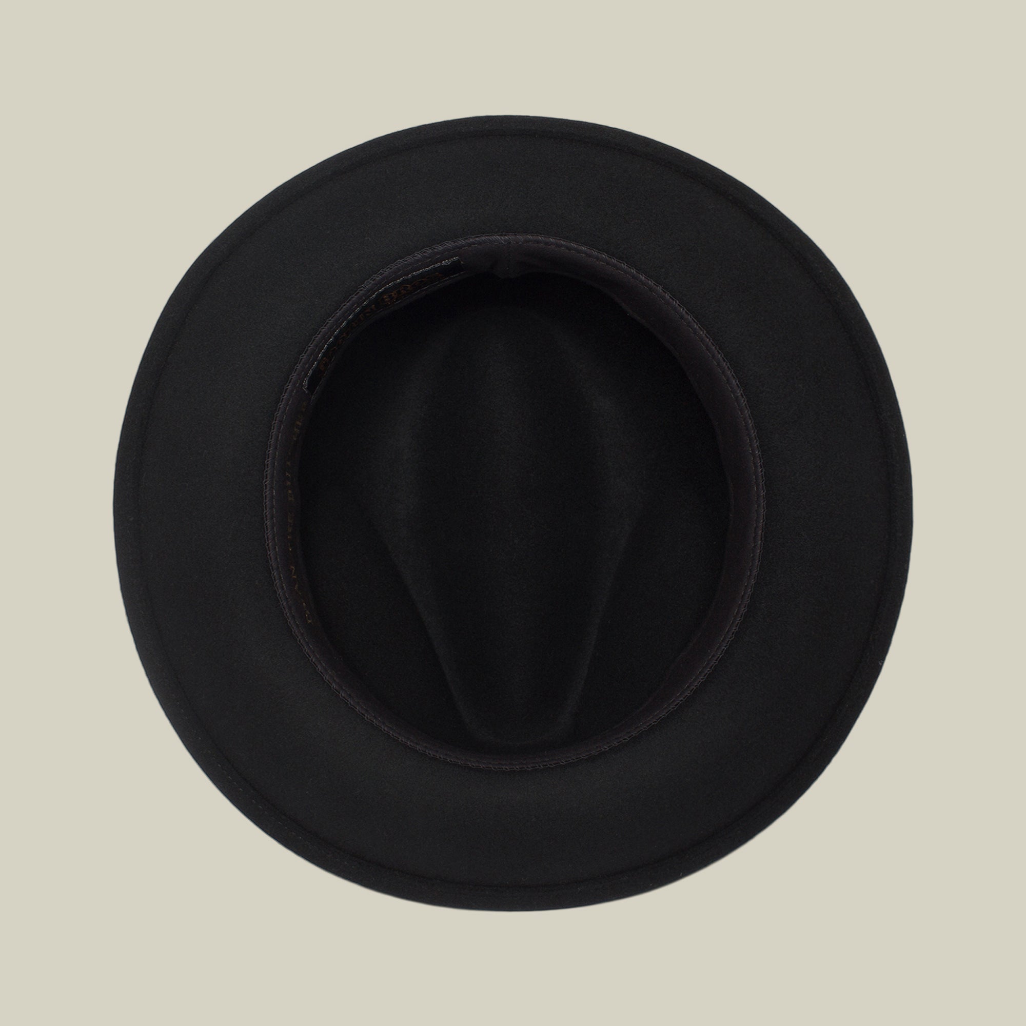 Top view of "Dean the Butcher" fedora by Goorin Bros., featuring a curved brim and sleek grosgrain hatband, displayed on a plain beige background.