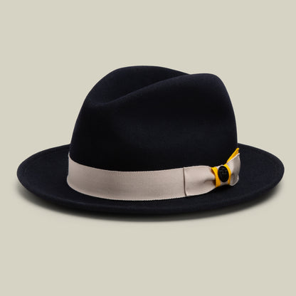 Expertly crafted in the USA, Dean the Butcher by Goorin Bros. is a striking EDGE-colored fedora featuring a wide, light gray ribbon and a small decorative button, elegantly showcased against a simple light background. This all-season hat seamlessly combines timeless style with versatile functionality.
