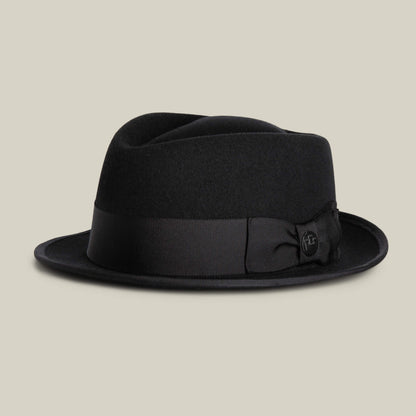 The Goorin Bros. Slick Carter is a black wool short brim fedora with a wide grosgrain ribbon and bow, channeling effortless style, shown against a plain light background.