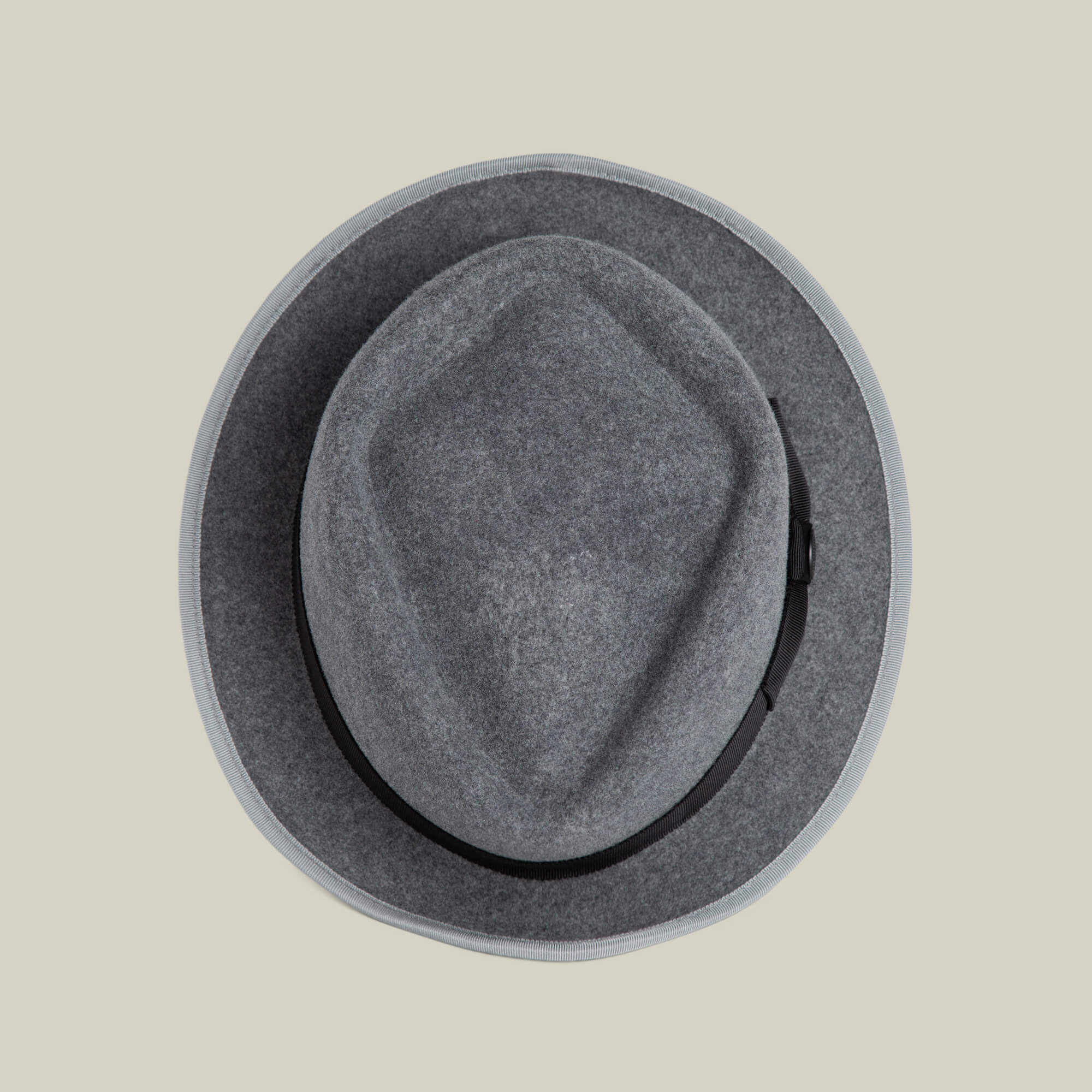 The Goorin Bros. Slick Carter is a grey wool short brim fedora with a black band, shown from above on a beige background—an accessory that captures effortless style.
