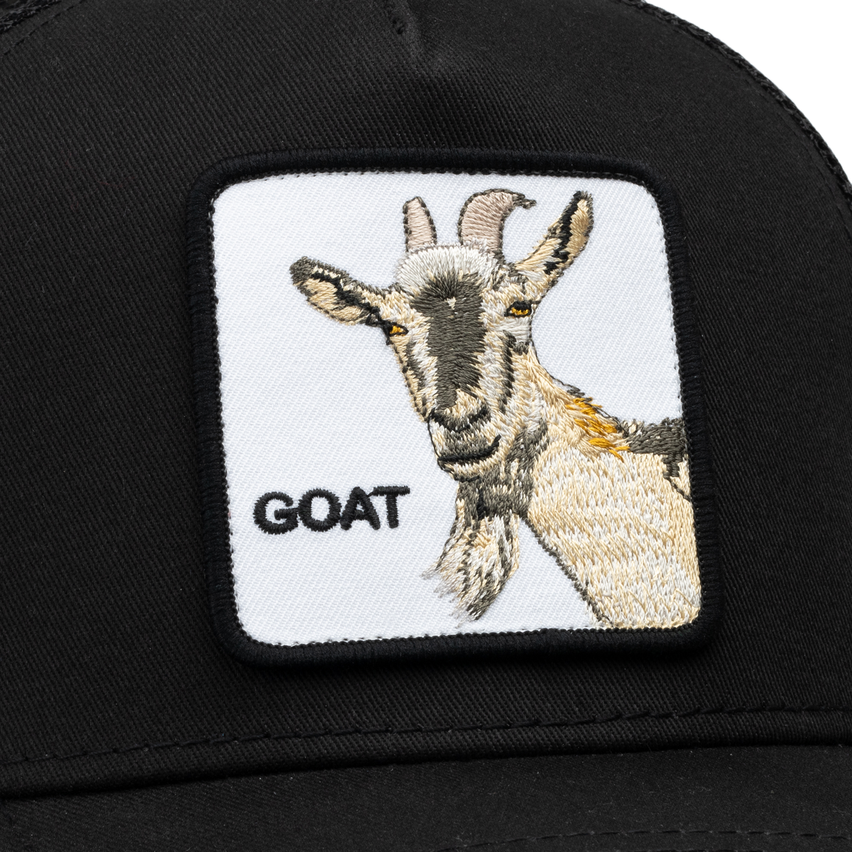 A close-up of a black Goat Beard trucker hat by Goorin Bros., featuring a mesh back and an embroidered patch with a goat and the word GOAT in capital letters.