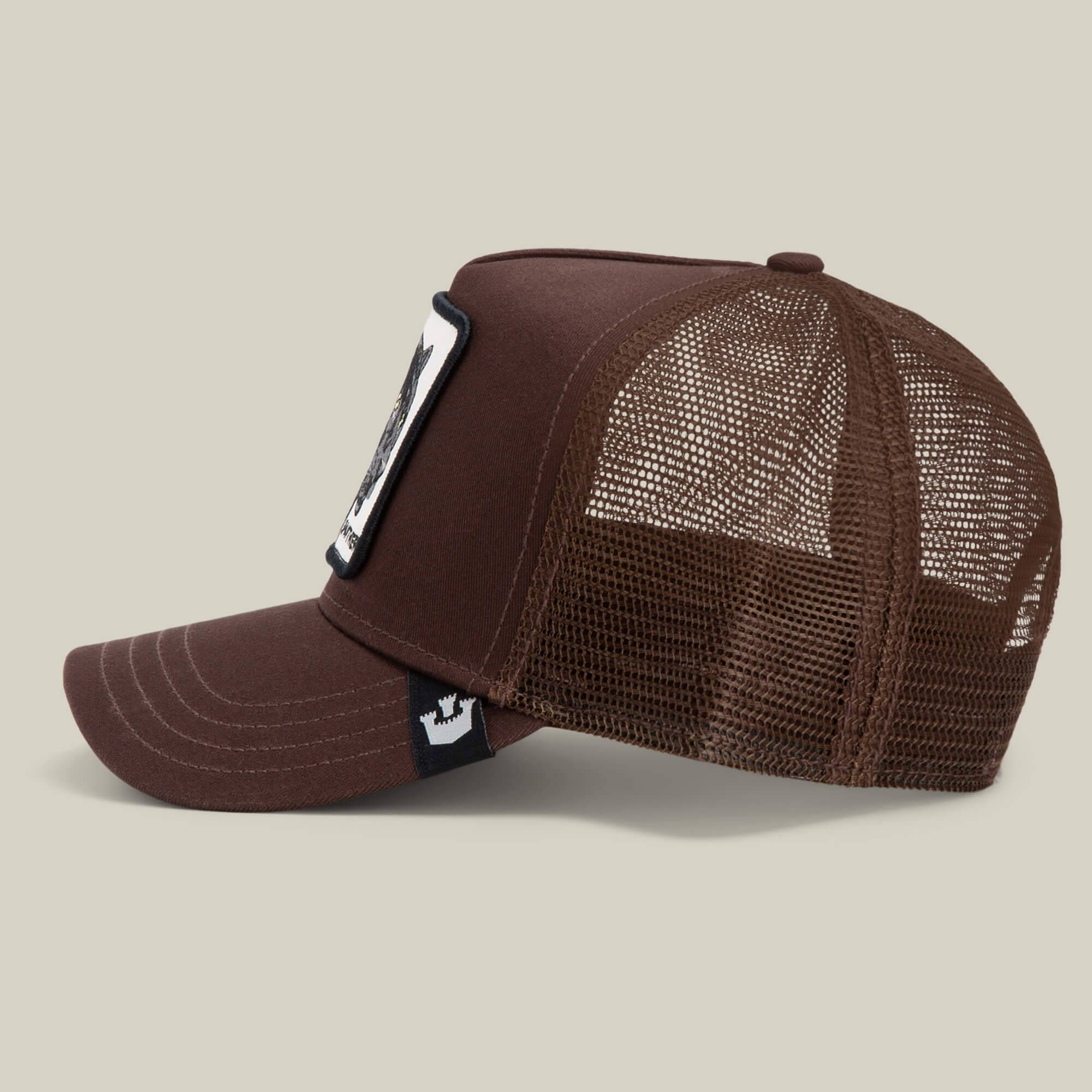 Brown "The Panther" trucker hat by Goorin Bros. features a mesh back, curved brim, and a rectangular front patch; shown from the side against a plain background.