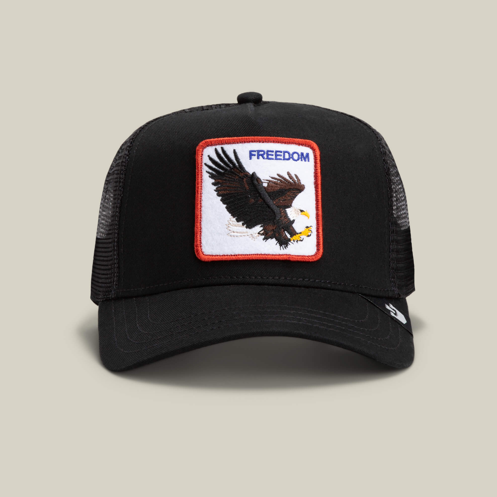 The Freedom Eagle by The Farm is a black mesh trucker hat featuring a front patch with an eagle in flight and the word "FREEDOM" in blue—a bold reminder to soar at a safe distance.
