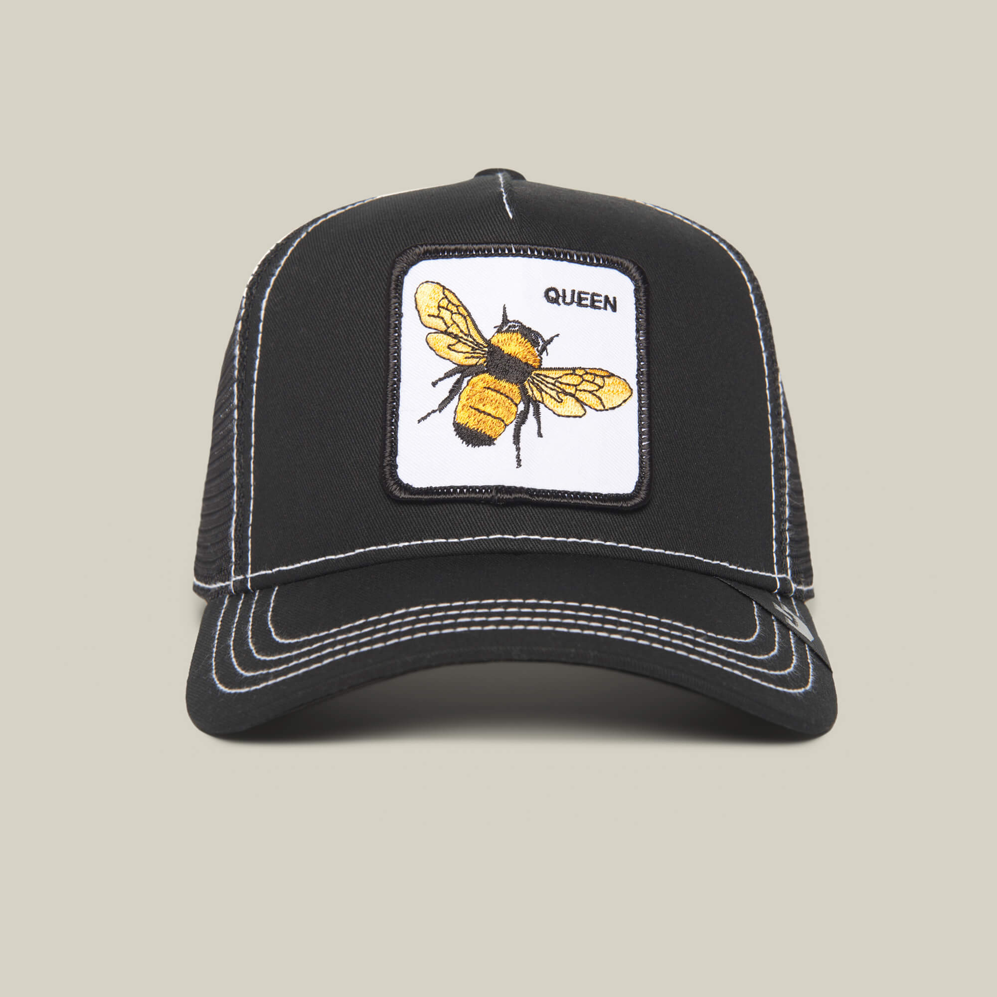 The Queen Bee by The Farm: A black trucker hat with white stitching, accented by a yellow bee patch and “QUEEN”—a stylish crown for those ready to slay.