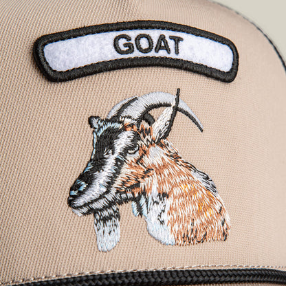 Close-up of The Farm GB2 Goat beige fabric Trucker Hat with an embroidered goat's head and a GOAT patch above it in black letters—a true badge of honor for champions.