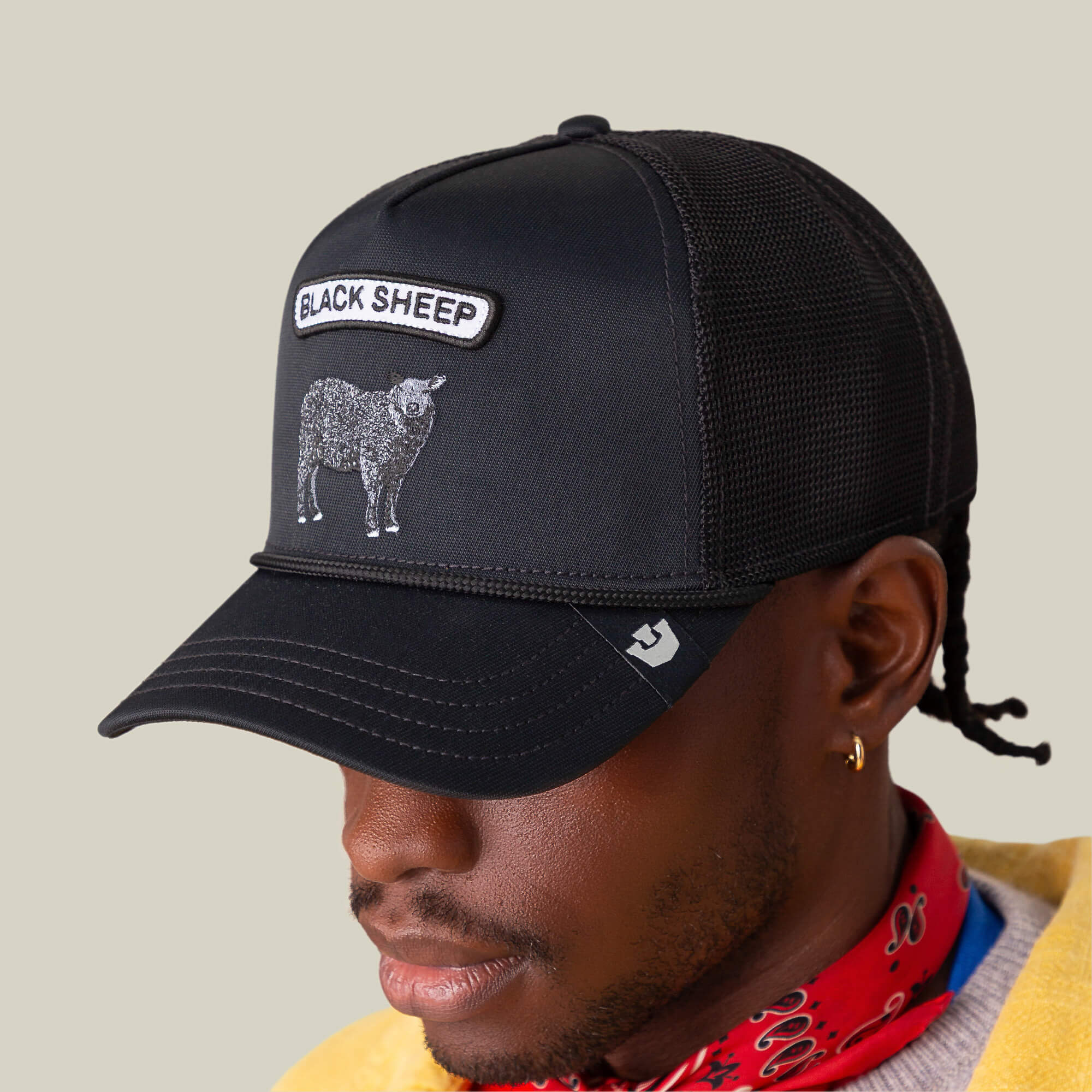 Wearing The Farm’s GB2 Black Sheep black mesh trucker hat with its bold sheep patch, plus a red patterned bandana and gold earring, this person channels custom mod style with effortless cool.
