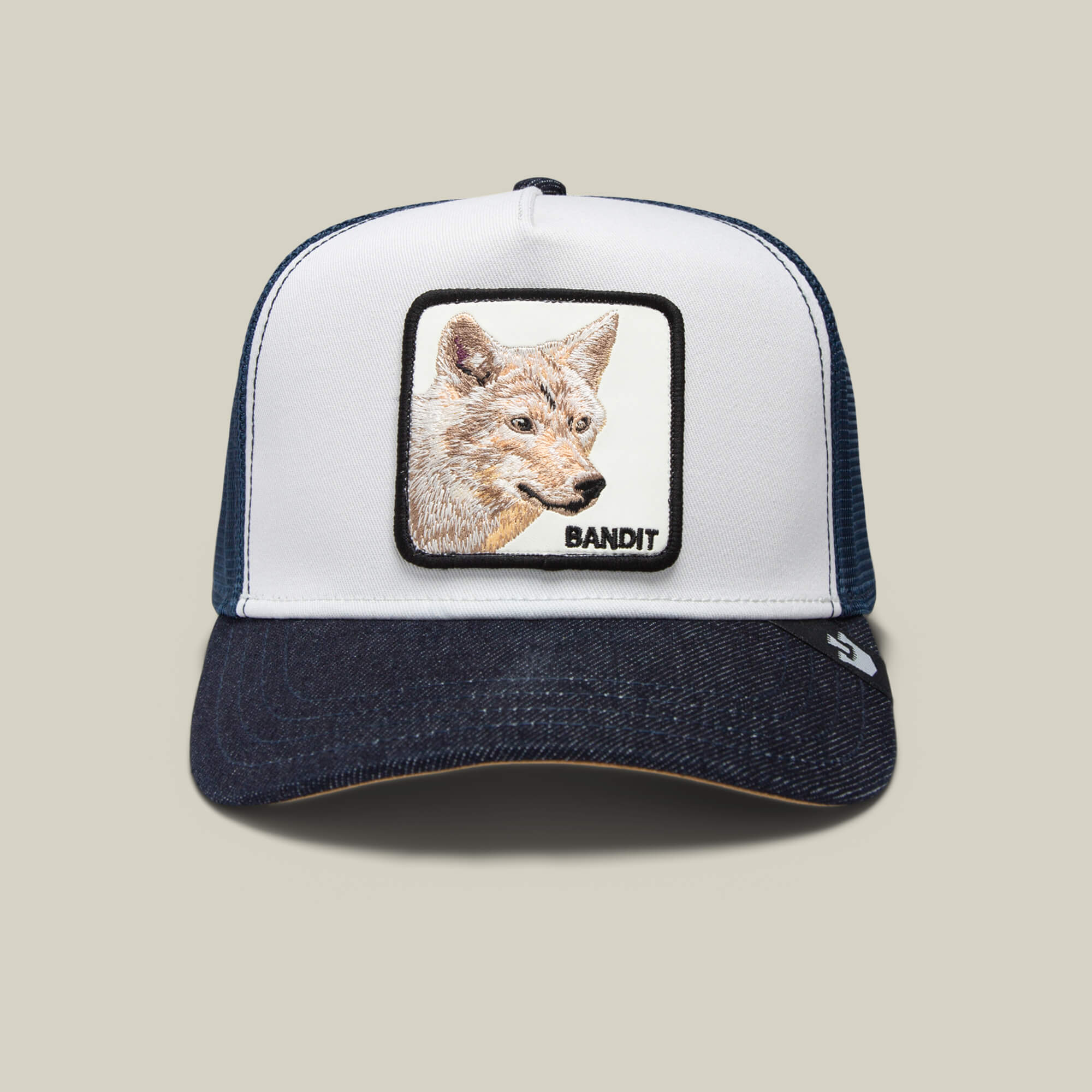 The Farm's "The Bandit Coyote" navy and white trucker hat showcases a front patch with an embroidered coyote face and the word BANDIT, offering rebel style and wild spirit.