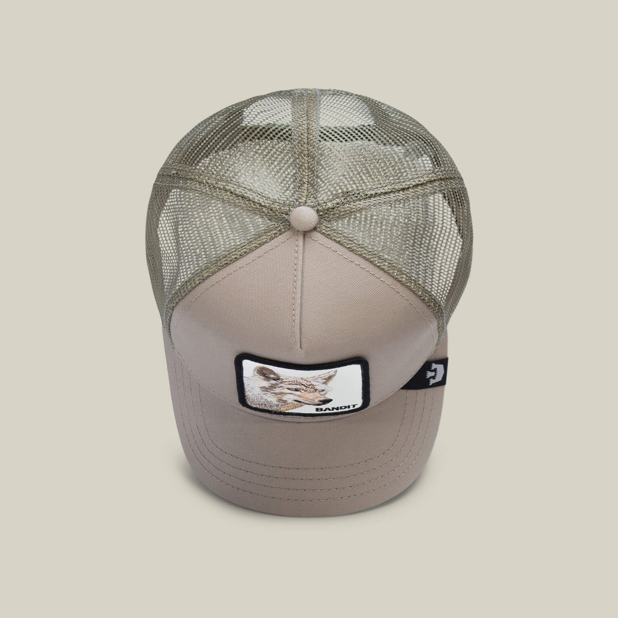 The Bandit Coyote by The Farm is a beige trucker hat with a mesh back and a front patch featuring a coyote and "BANDIT"—ideal for those with a wild spirit and adventurous style.