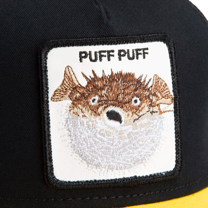A close-up of The Farm’s “The Puff Puff Fish” black hat, featuring a patch with an embroidered pufferfish and “PUFF PUFF” text; all sales are final.