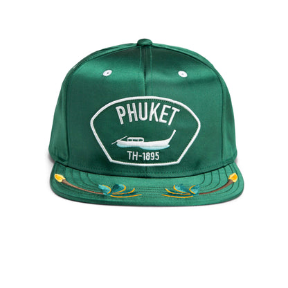 Green baseball cap with Phuket, an airplane graphic, and TH-1895 embroidered on the front, plus decorative stitching on the brim—a durable hat inspired by classic American made style.