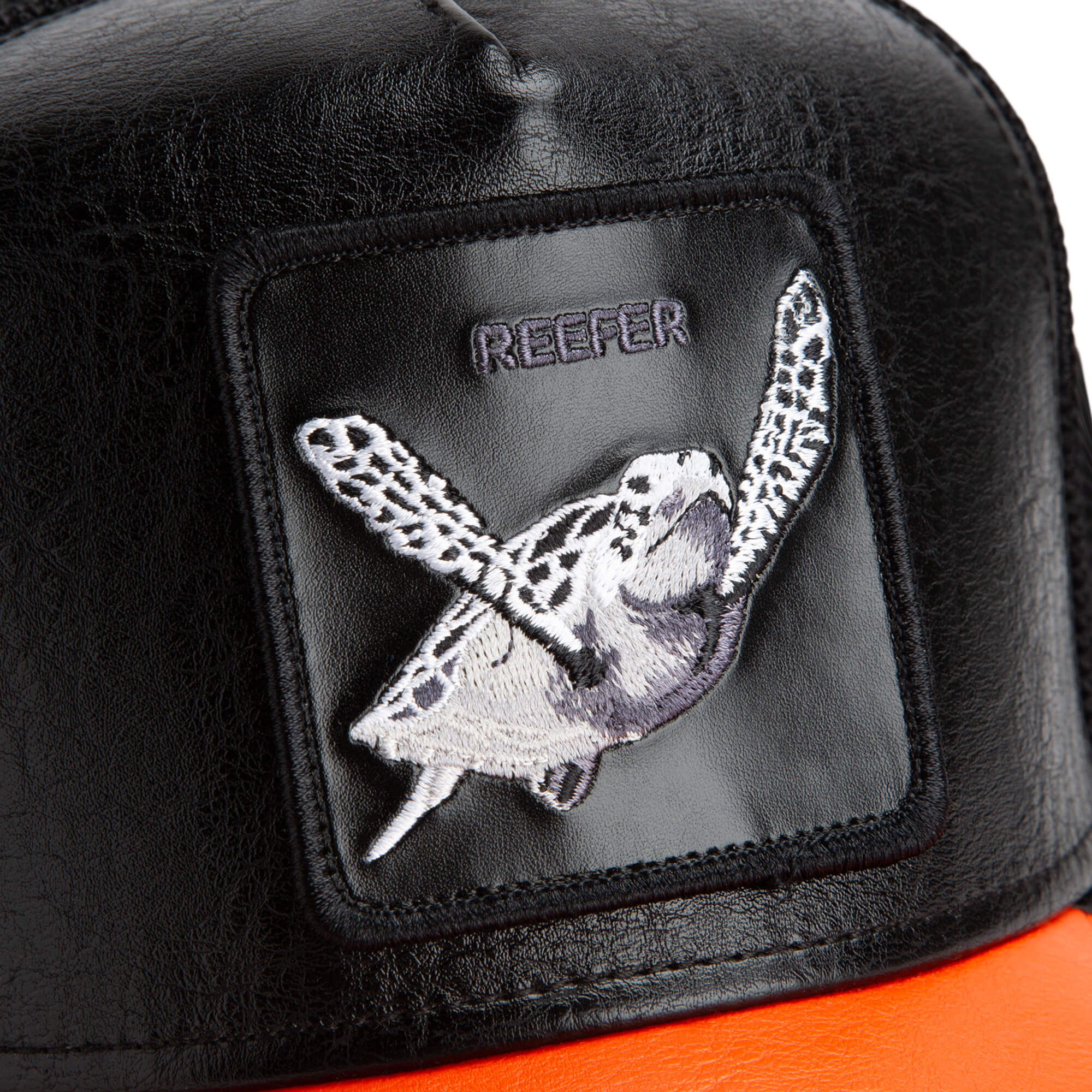 Close-up of The Farm's Shell Smoke hat: black with an embroidered sea turtle patch, "REEFER" above it, and an orange brim. All sales final.