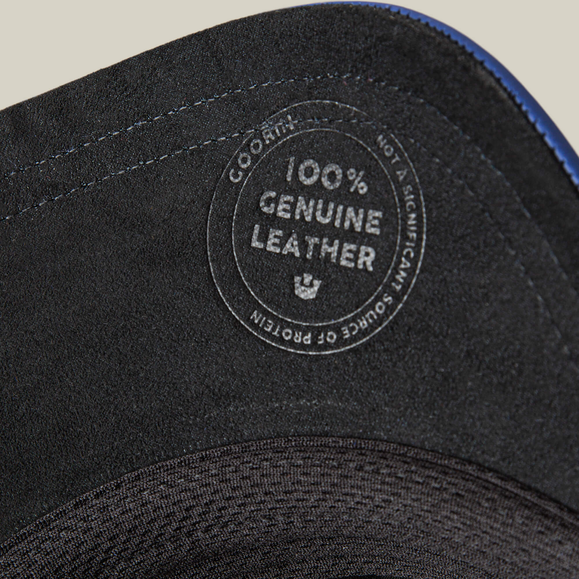 Close-up of the Goorin Bros. LFG Stallion, a black leather item with royal blue stitching and a "100% Genuine Leather - Not a Significant Source of Protein" stamp. Blue stitching lines the edge.