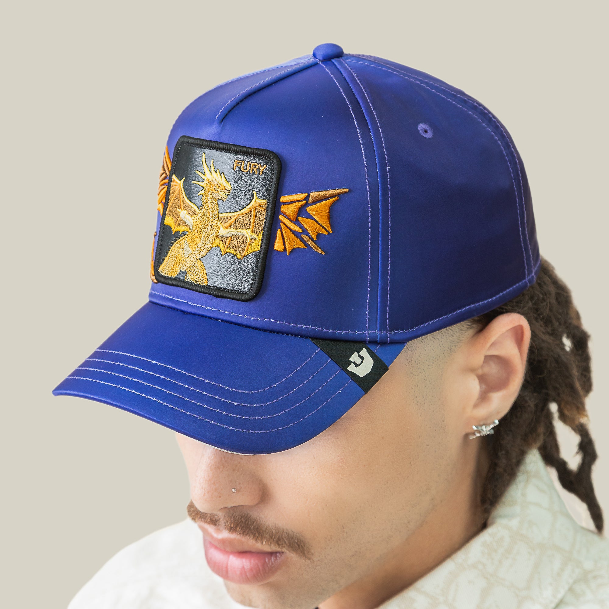 A person wears the Goorin Bros. Hell Hath No cap in royal blue ombre, featuring bold dragon embroidery and a FURY patch on the front.