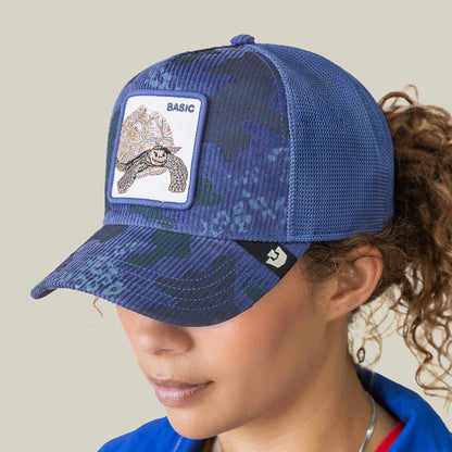 A person wears the Goorin Bros. Turtle Camo cap, a blue camo corduroy hat with a mesh back and a patch featuring a tortoise and the word "BASIC.