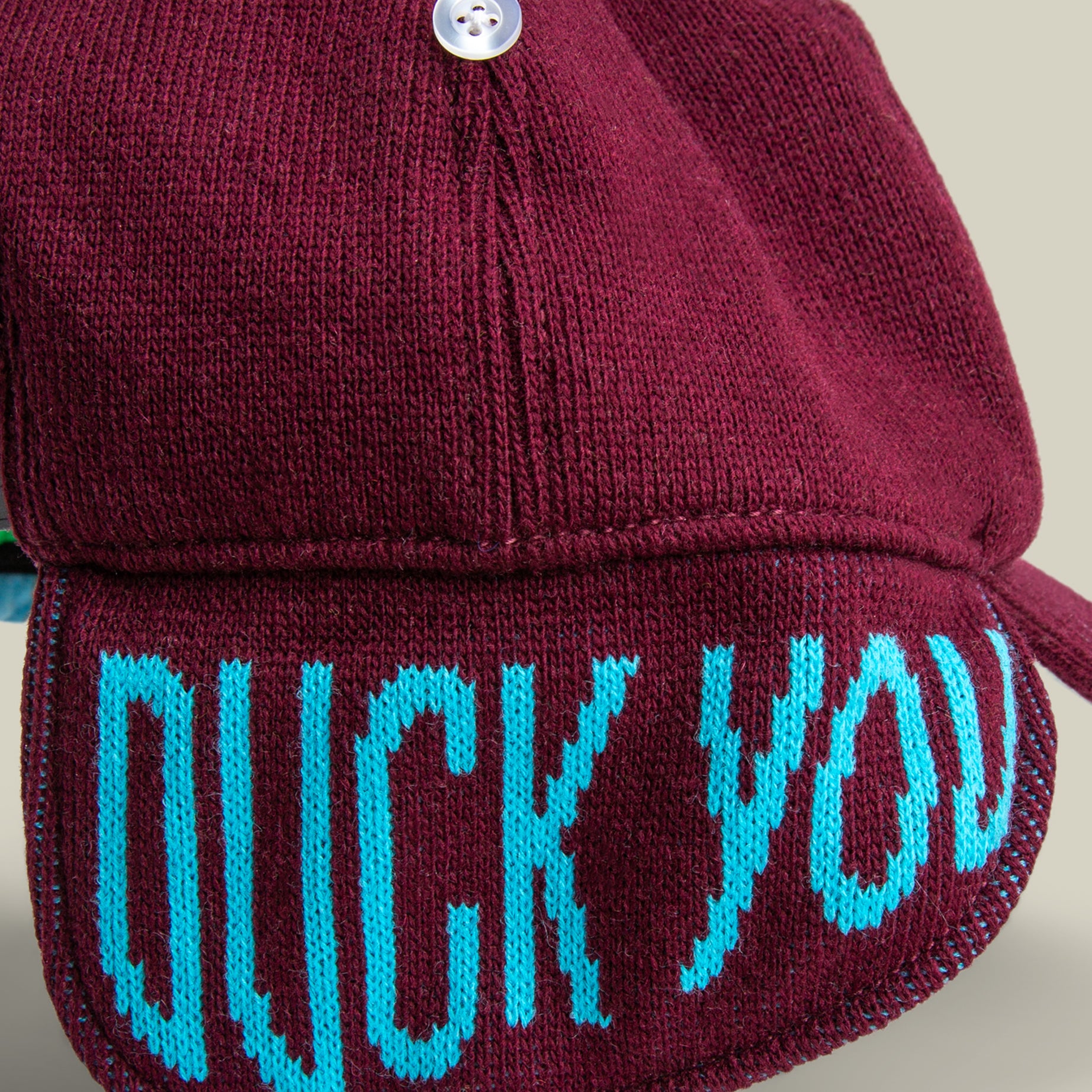 The "F is for Duck" hat by Goorin Bros. is a maroon knit with a button on top and “DUCK YOU” in bold blue letters on the brim—perfect for witty winter style or as an autocorrect-themed accessory.