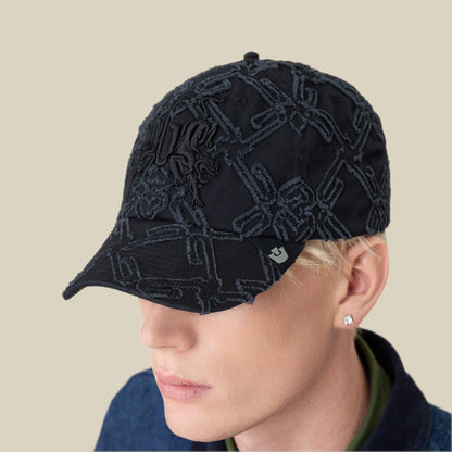 A person with short blond hair wears the Goorin Bros. Future Baby Daddy Papa Cap with all-over embroidery and a stud earring, looking partially downward against a beige background.