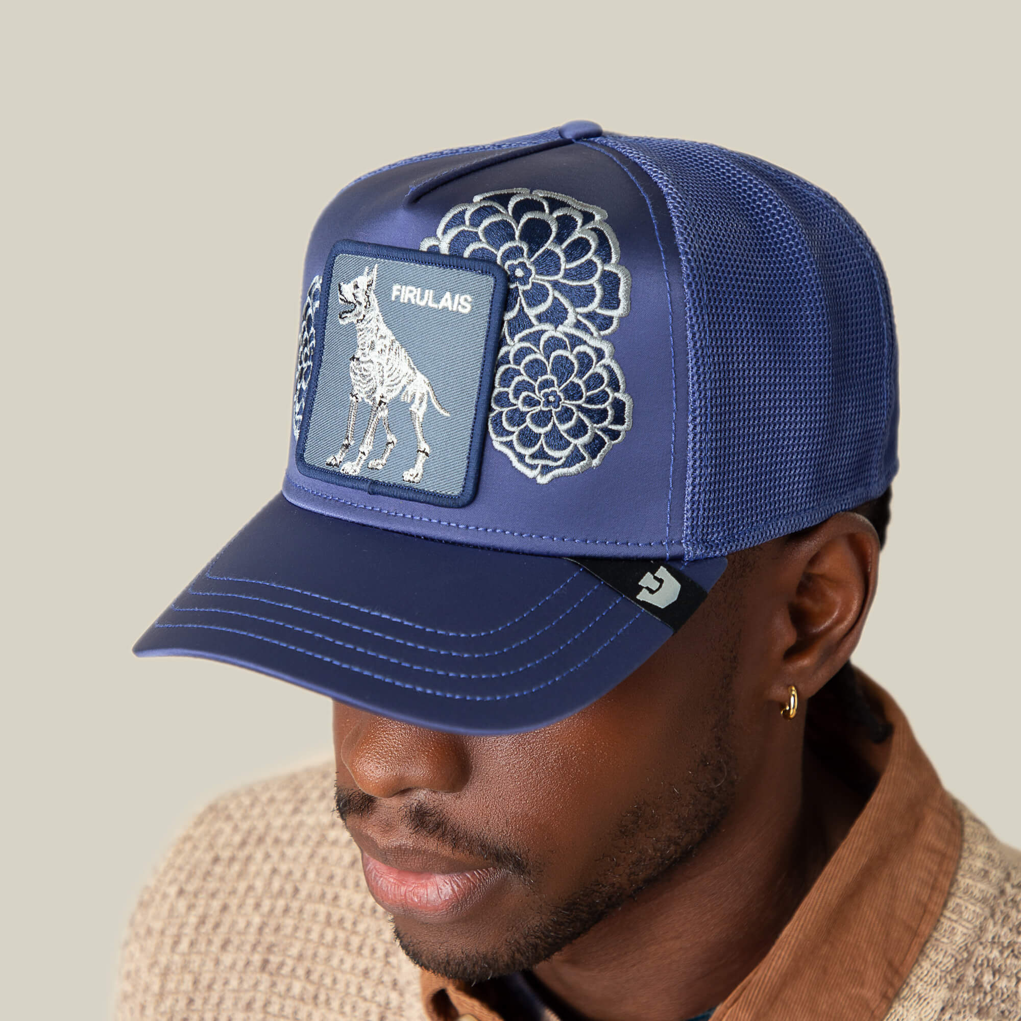 A person wears Goorin Bros.' Dia De Firulais blue mesh cap, featuring floral embroidery and a skeletal dog patch with "Firulais"—a stylish choice for Life After Ordinary fans.