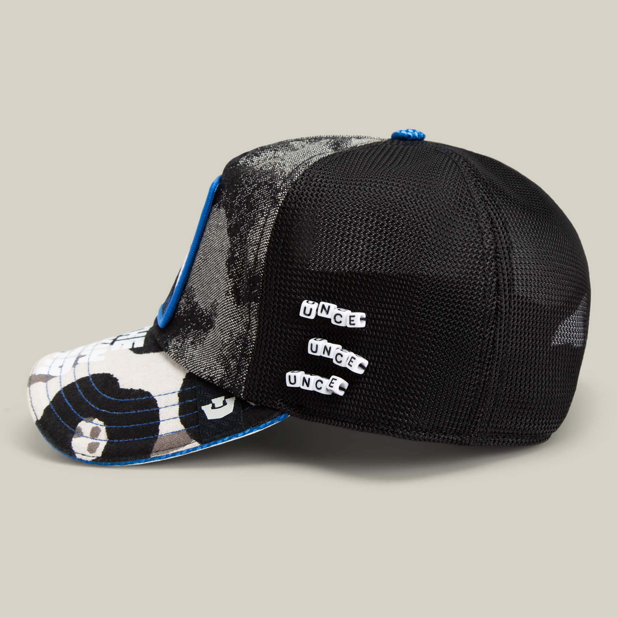 The Goorin Bros. Techno is a black mesh trucker cap featuring a blue and white camouflage front, blue trim, and three UNCE pins—making it the ideal festival fashion statement piece.