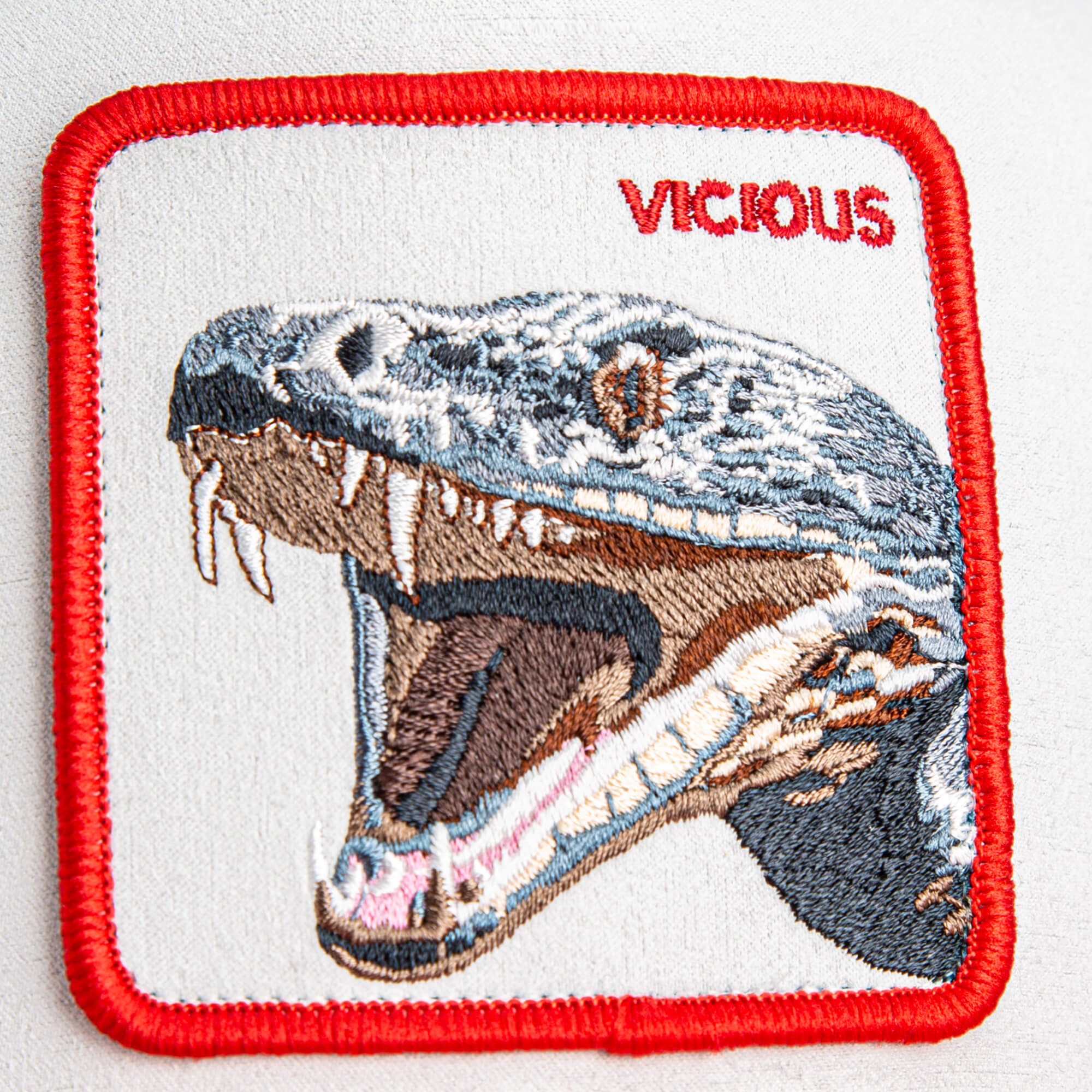 The Goorin Bros. Suede Snake patch features an open-mouthed, snarling snake and the word "VICIOUS" in bold red—smooth to the touch and ideal for customizing your premium trucker hat.