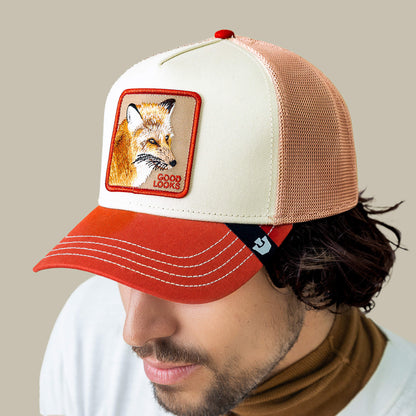 A man wears the Goorin Bros. Tricolor Fox trucker hat—featuring a fox patch and "GOOD LOOKS" text—styled with a brown turtleneck and white shirt.