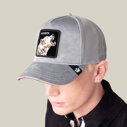 A person with light skin and blond hair lounges in a gray mesh baseball cap from Goorin Bros. featuring a Velour Wolf patch, adding standout style and a main event vibe to the velvet texture of their look.