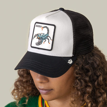 A person wearing the Goorin Bros. "Deadly" black and white mesh hat with a patch featuring an embroidered scorpion.